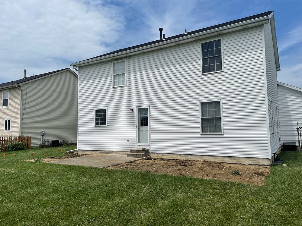 Deck addition — during: old deck removed, backyard cleared with orange stakes marking new deck footprint and patio door opening framed, Findlay, Ohio