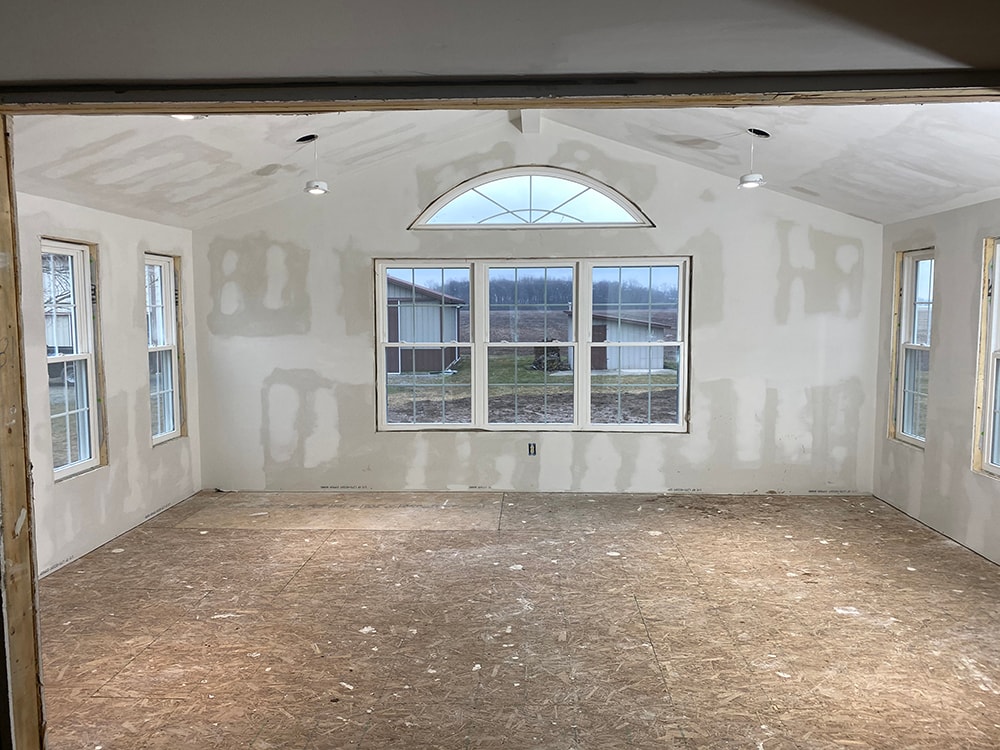 Room addition Fostoria — interior wide view from doorway showing full room with vaulted ceiling, arched window, and picture window wall, Fostoria, Ohio