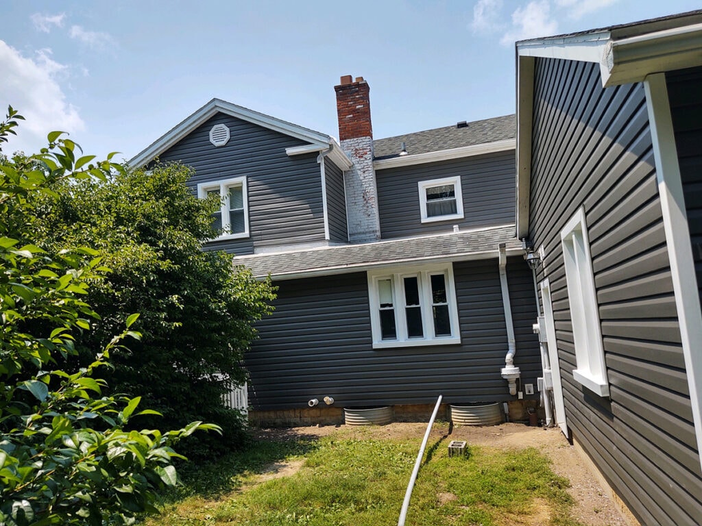 Hancock Park District siding — after: rear view of Welcome Center with new dark charcoal vinyl siding and brick chimney, Findlay, Ohio