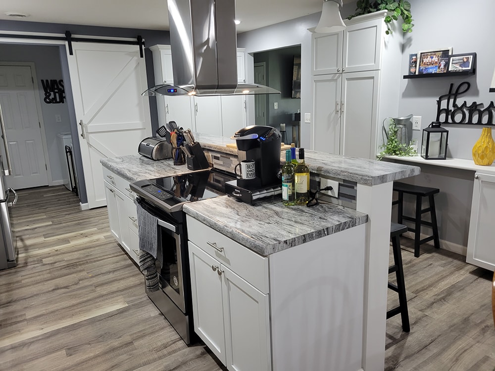 Kitchen remodel Findlay — after: island with cooktop, exhaust fan, and barn door, Findlay, Ohio