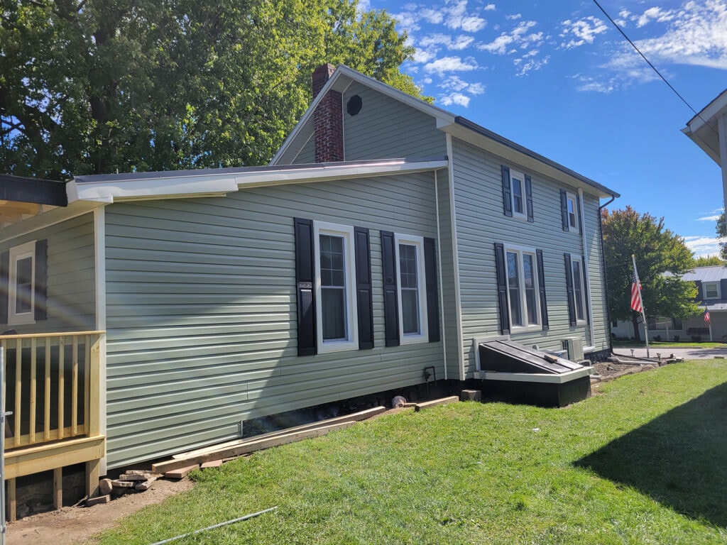 New siding and deck — after, rear side view showing new sage green siding and new back deck framing, Benton Ridge, Ohio