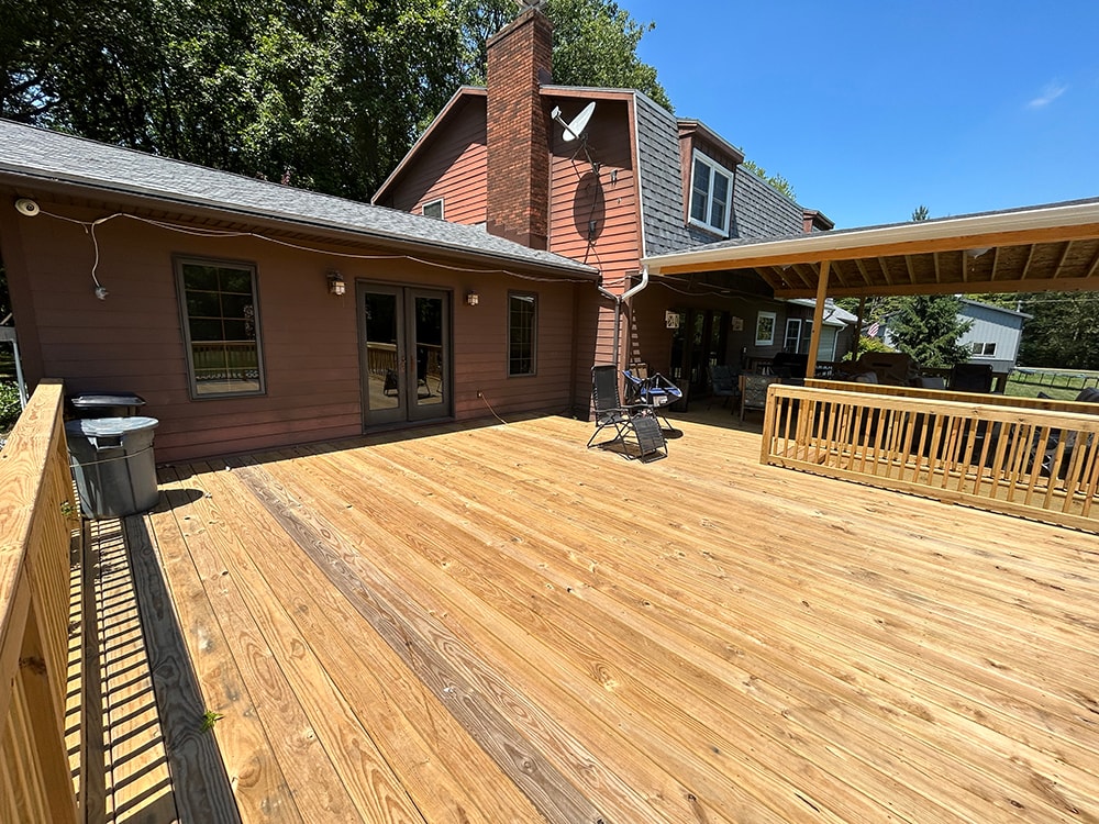 New treated deck with gable — open deck surface with French doors and covered section beyond