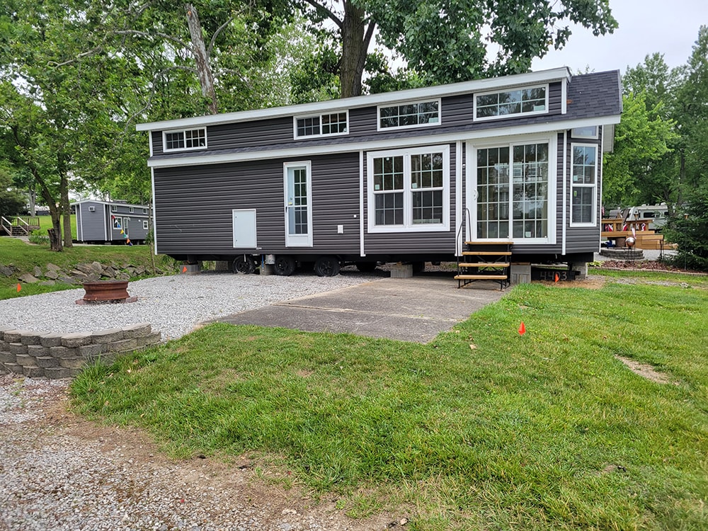 New treated deck — before: dark gray park model with temporary entry steps and no deck — Wapakoneta campground