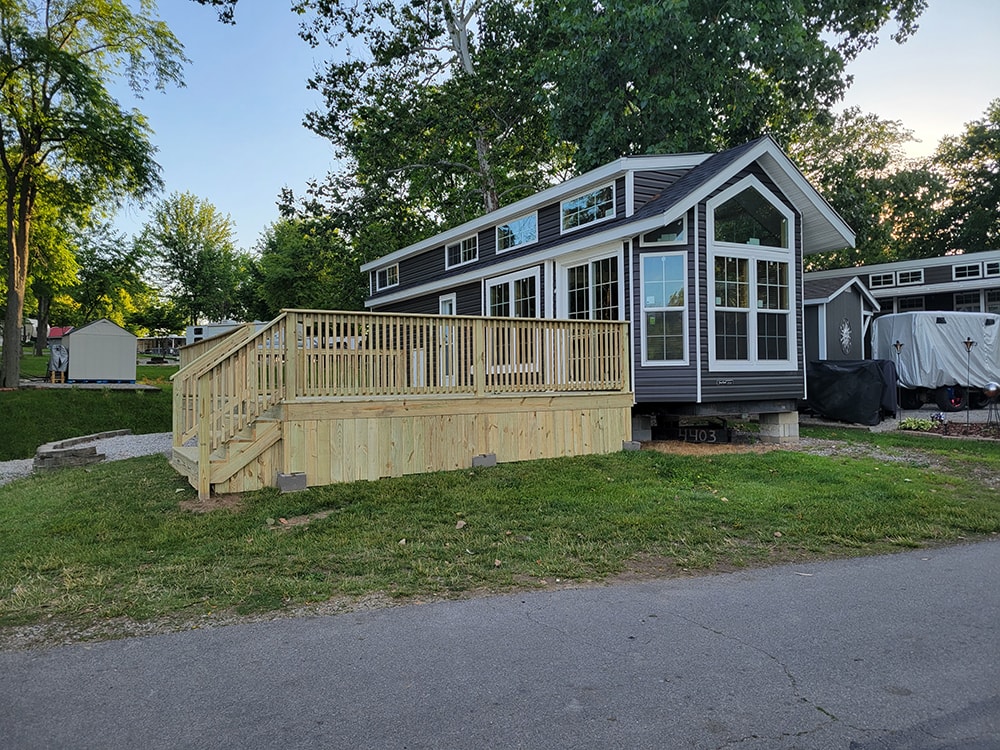 New treated deck — after: dark gray park model with completed treated wood deck and staircase — Wapakoneta campground