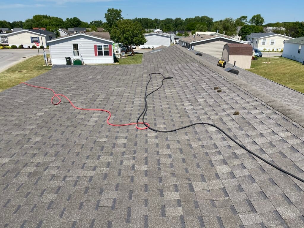 Roof addition existing deck Findlay — during: aerial view of new gray architectural shingles installed on home roof with nail gun hoses laid across surface, neighborhood in background, Findlay, Ohio