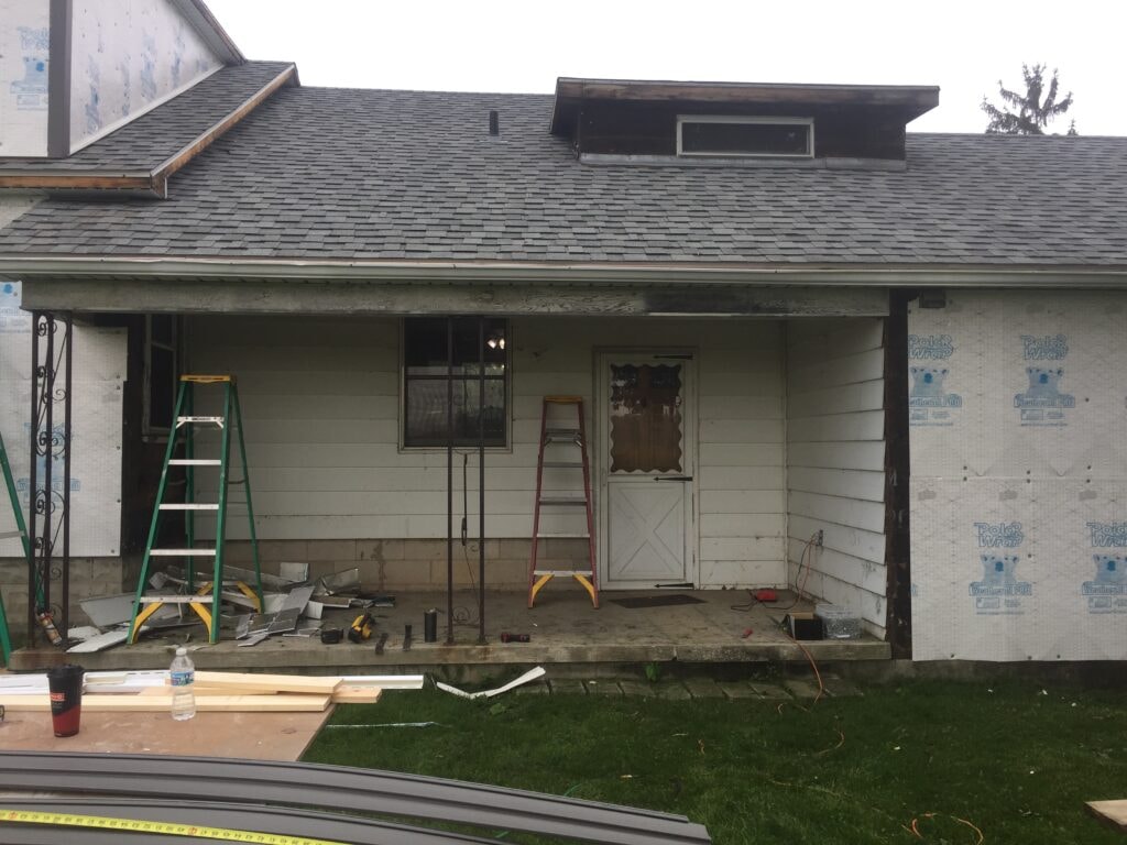 Siding and new windows Findlay — during: front porch stripped to PolarWrap house wrap with ladders and old siding removed, Findlay, Ohio