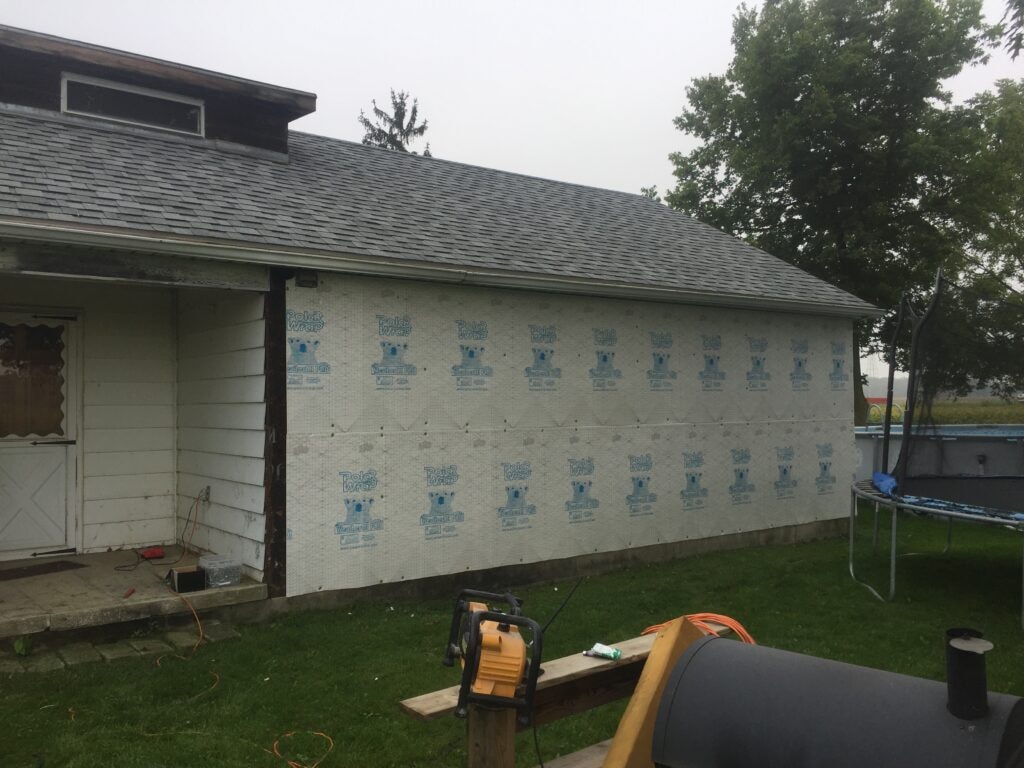 Siding and new windows Findlay — during: side of home wrapped in PolarWrap house wrap with old siding fully removed, Findlay, Ohio