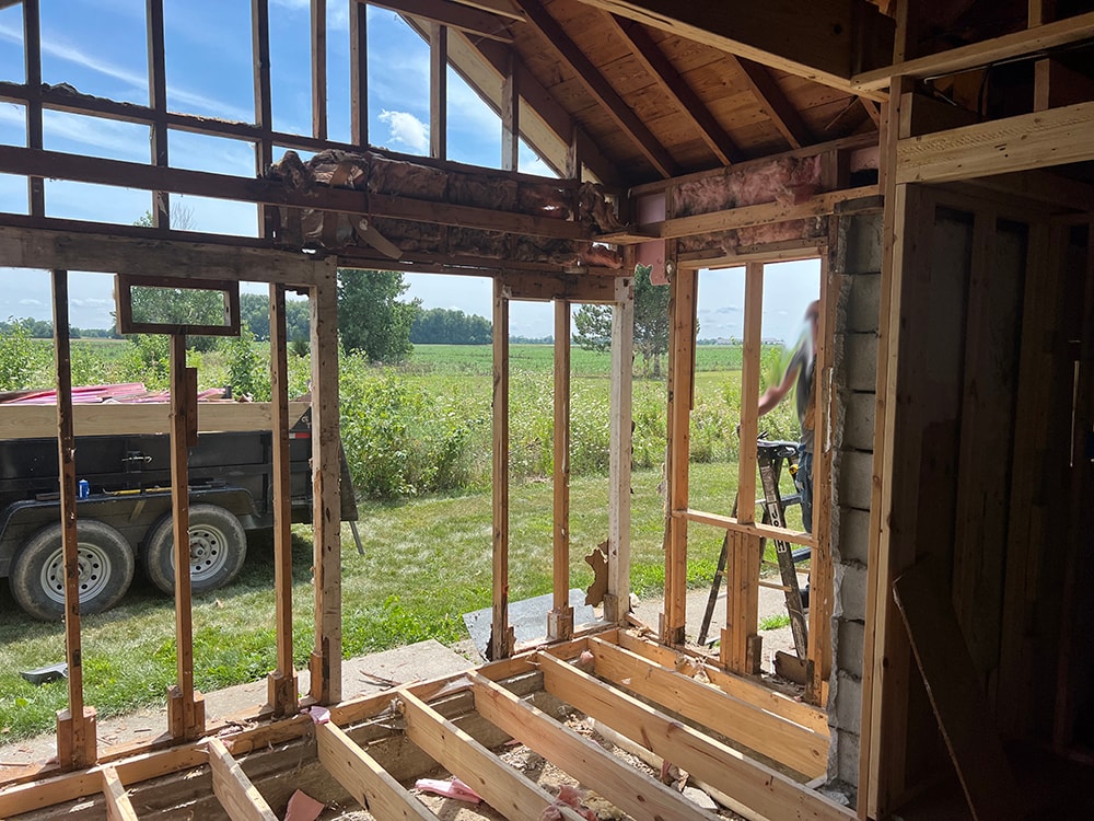 Small room reframe — interior demo, old framing stripped to studs with open wall to exterior and crew working, Findlay, Ohio