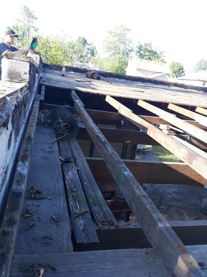 TPO roof replacement Findlay — during: Woodruff Contracting crew member removing old rotted roof decking and framing boards with power drill, Findlay, Ohio